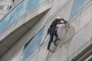 Man cleaning office block windows on a harness Commercial Window Cleaning